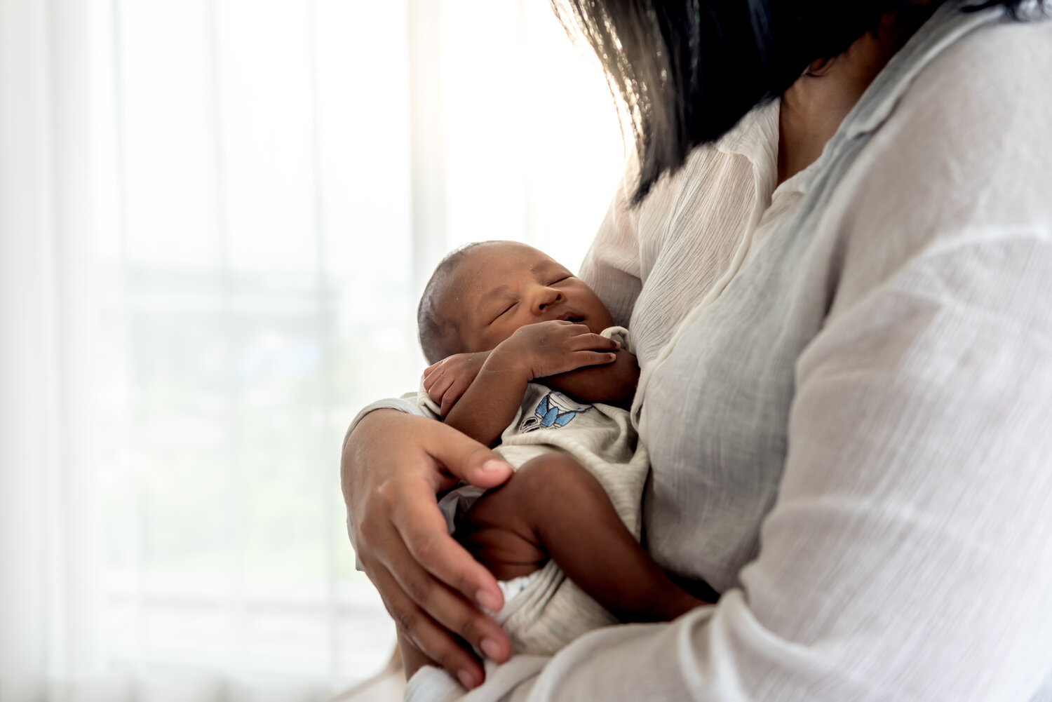 Portrait images of half African half Thai, 12-day-old baby newborn son, sleeping with his mother being held, to family and infant newborn concept.