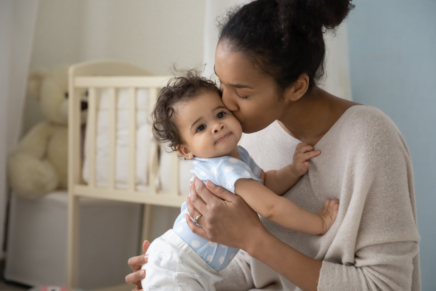 Loving young african American mother hold little newborn infant child kiss